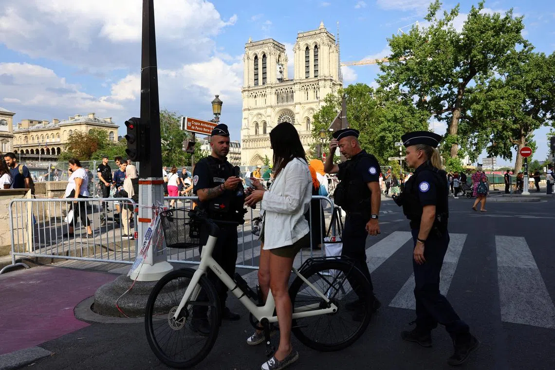 A police officer checks a person's ID near Paris' Notre Dame Cathedral on July 19 as the security perimeter for the opening ceremony is deployed ahead of the July 26-Aug 11 Olympics. 