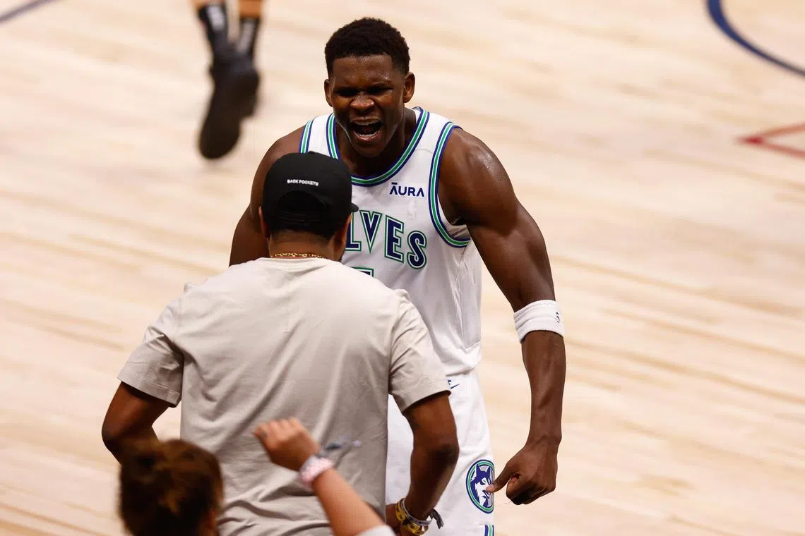 Minnesota Timberwolves guard Anthony Edwards celebrating with a fan after making a three-point basket during the fourth quarter of Game 7 of the Western Conference semi-final series between the Minnesota Timberwolves and the Denver Nuggets at Ball Arena on May 19. The Timberwolves won the game 98-90 to win the series 4-3 and advance to the Western Conference finals. 