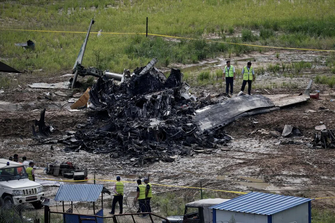 FILE PHOTO: Officials from the airport stand near the wreckage of a Saurya Airlines plane that caught fire after skidding off the runway while taking off at Tribhuvan International Airport, in Kathmandu, Nepal, July 24, 2024. REUTERS/Navesh Chitrakar/File Photo