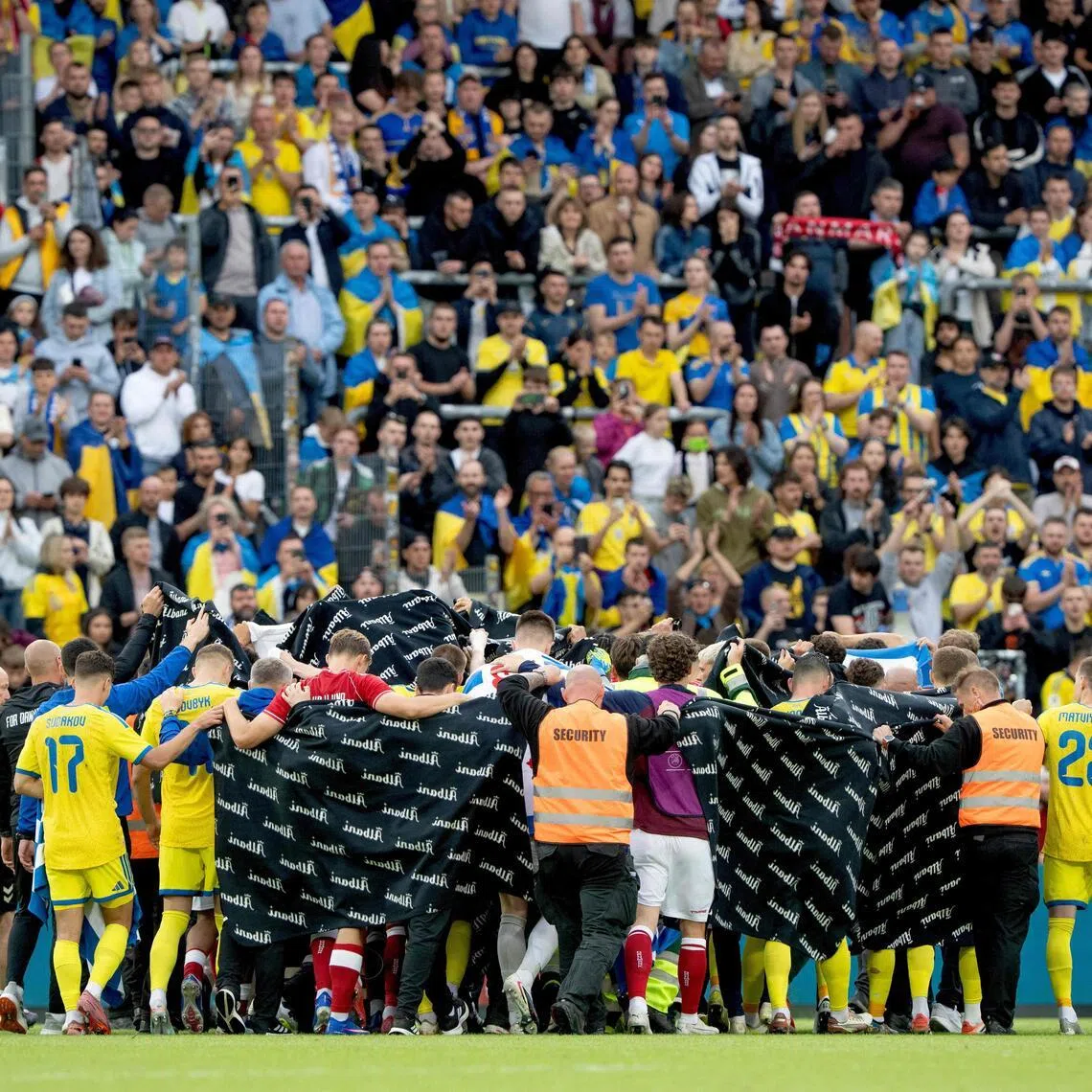 Denmark and Ukraine's players huddling to accompany Denmark's midfielder Christian Eriksen to a waiting ambulance during the international football friendly match between Denmark and Ukraine at Odense Stadium in Denmark, on June 7, 2026.