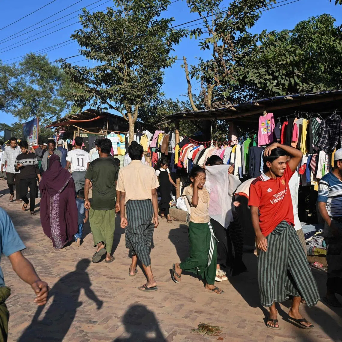 This photograph taken on Dec 18, 2025 shows Rohingya refugees walking along a market at the Kutupalong refugee camp in Bangladesh's Ukhia.