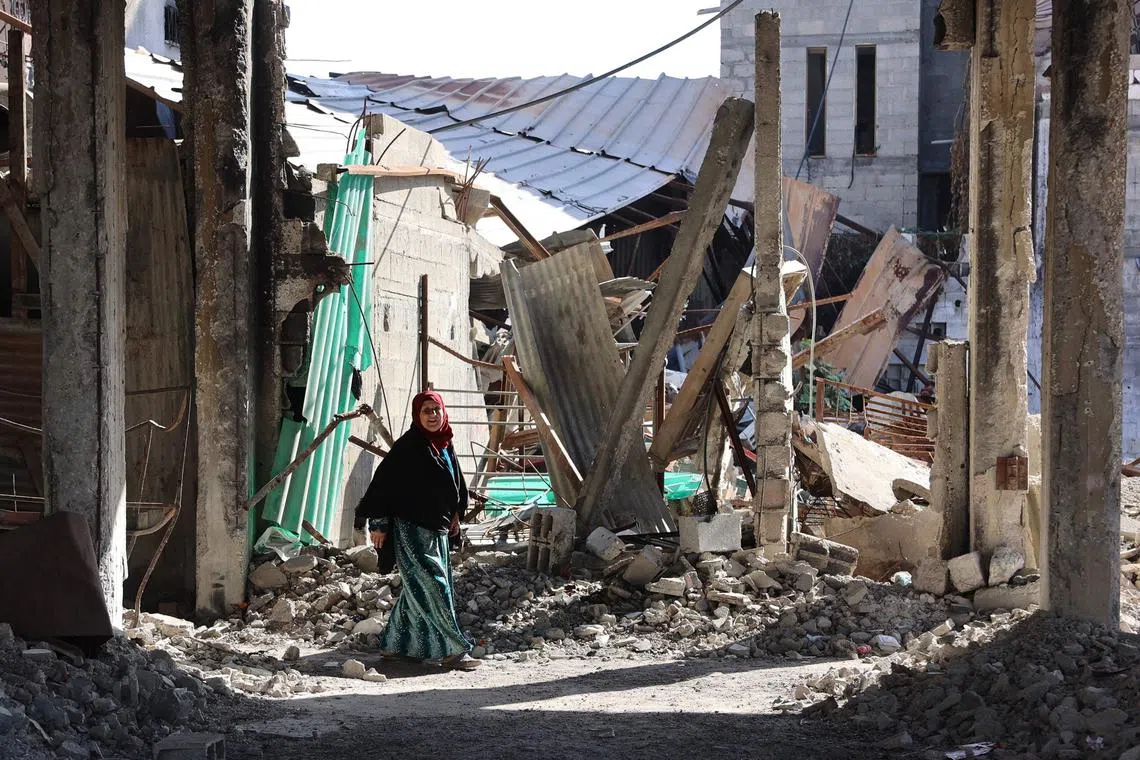 A Palestinian woman walks in a destroyed building in Jabalia in the northern Gaza Strip.