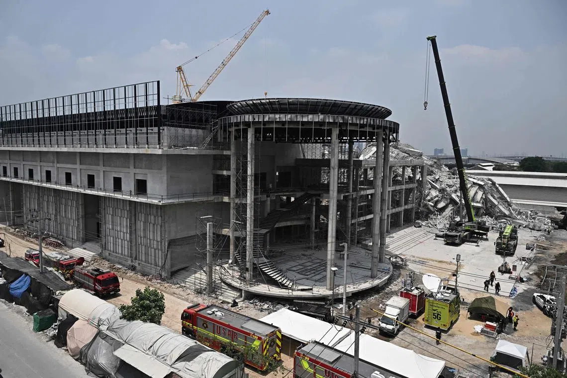 Heavy construction equipment and rescue vehicles are pictured at the site of an under-construction building collapse in Bangkok on March 29.