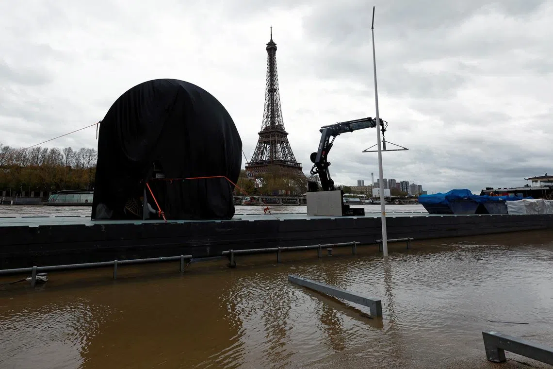 A view shows the Paris 2024 Olympic Games countdown clock covered with a tarpaulin and moved on a boat from the banks of the River Seine, near the Eiffel Tower, due to risks of flooding in Paris, France, April 5, 2024. REUTERS/Gonzalo Fuentes/File Photo