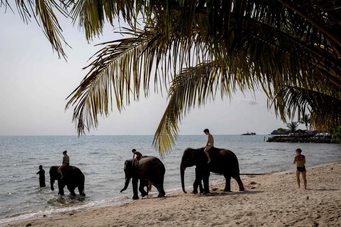 Tourists ride elephants on a beach on Thailand’s island of Koh Chang, on April 9, 2023.