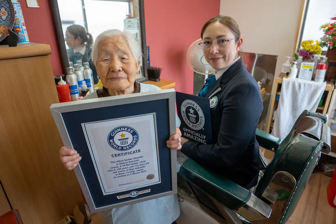 A Guinness World Records representative presents Ms Shitshui Hakoishi a certificate recognising her as the world's oldest barber at 108 years old.