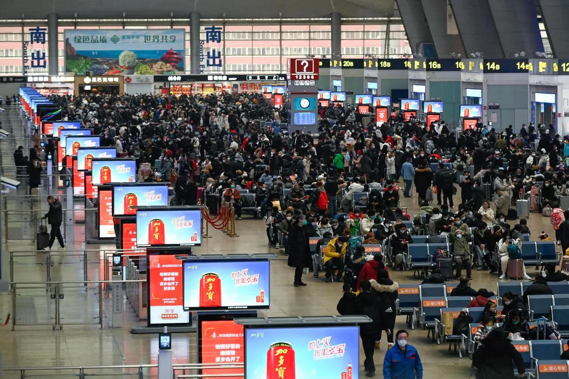 Passengers wait to check in at a railway station in Beijing on January 12, 2023, as the annual migration begins with people heading back to their hometowns for Lunar New Year celebrations. (Photo by WANG ZHAO / AFP)