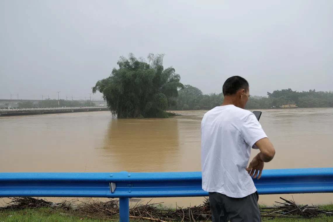 A resident uses his phone as he stands near a flooded river following heavy rainfall in Guangdong province on April 22.