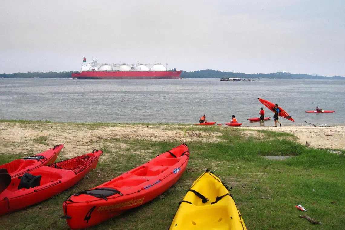 Canoes and canoeists at the Pasir Ris Beach. In the background is an LNG vessel navigating the East Johor Straits.
