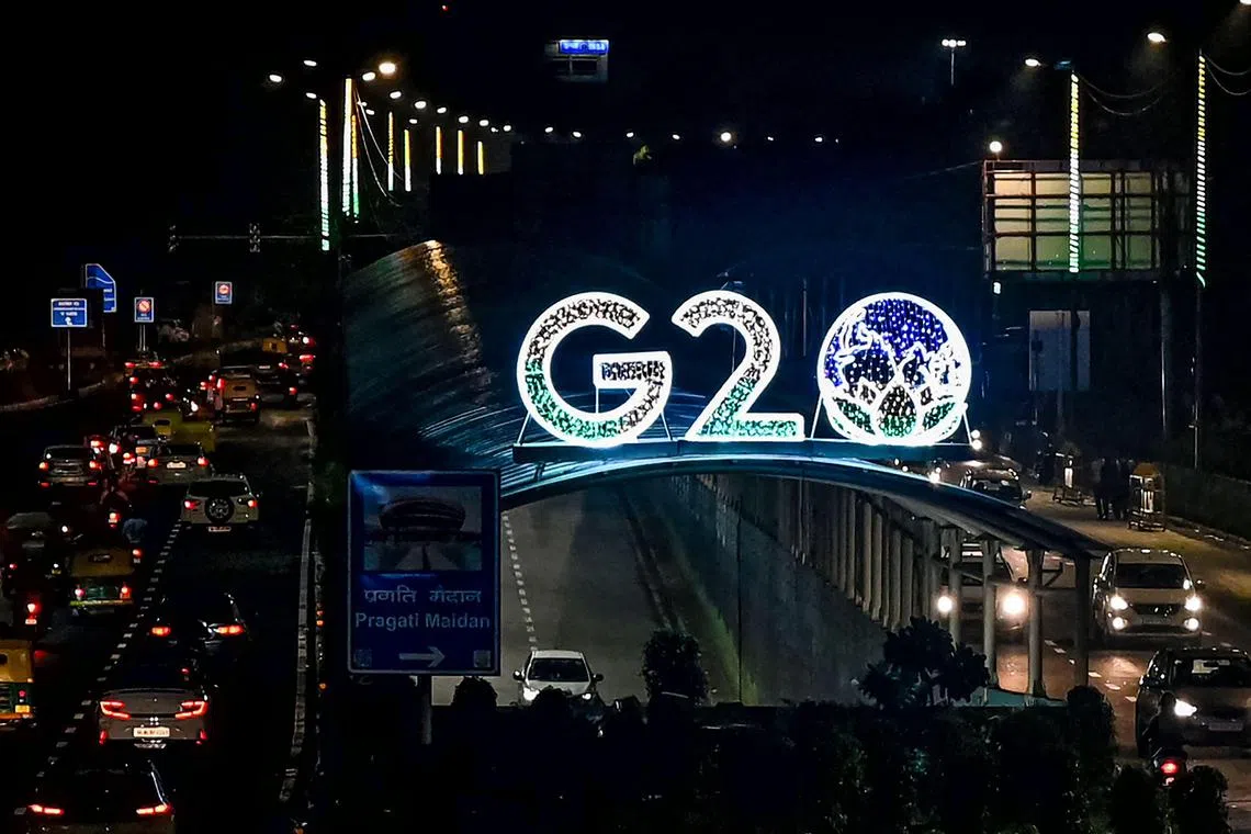 TOPSHOT - Vehicles drive past the logo of India's G20 summit, along a road in New Delhi on August 10, 2023. (Photo by Sajjad HUSSAIN / AFP)