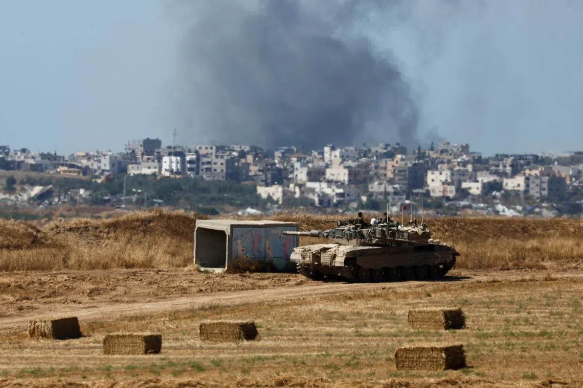 An Israeli tank holds a position as smoke rises in Gaza, amid the ongoing conflict between Israel and the Palestinian Islamist group Hamas, near the Israel-Gaza border, in Israel, May 15, 2024. REUTERS/Amir Cohen/ File Photo