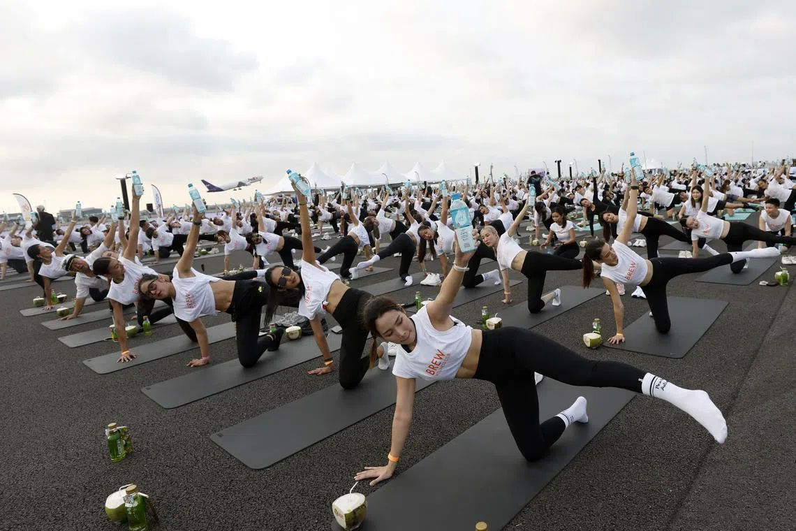 Yoga enthusiasts exercising as an aircraft takes off during a yoga event at the third runway of Suvarnabhumi International Airport on April 27. 