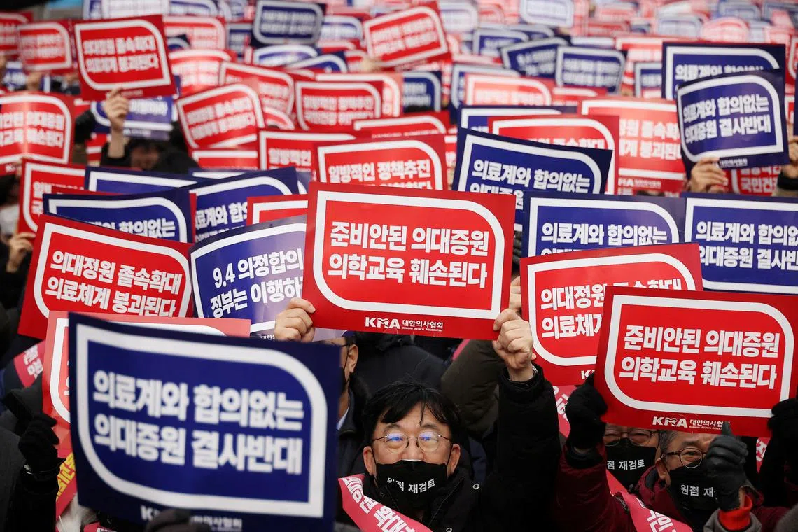 FILE PHOTO: Doctors chant slogans during a rally to protest against government plans to increase medical school admissions in Seoul, South Korea, March 3, 2024. The banners read \"Oppose increasing medical school admissions without talks with the medical community\" (in blue) and \"Medical education will be harmed in increasing medical school admissions\" (in red).  REUTERS/Kim Hong-Ji/File Photo