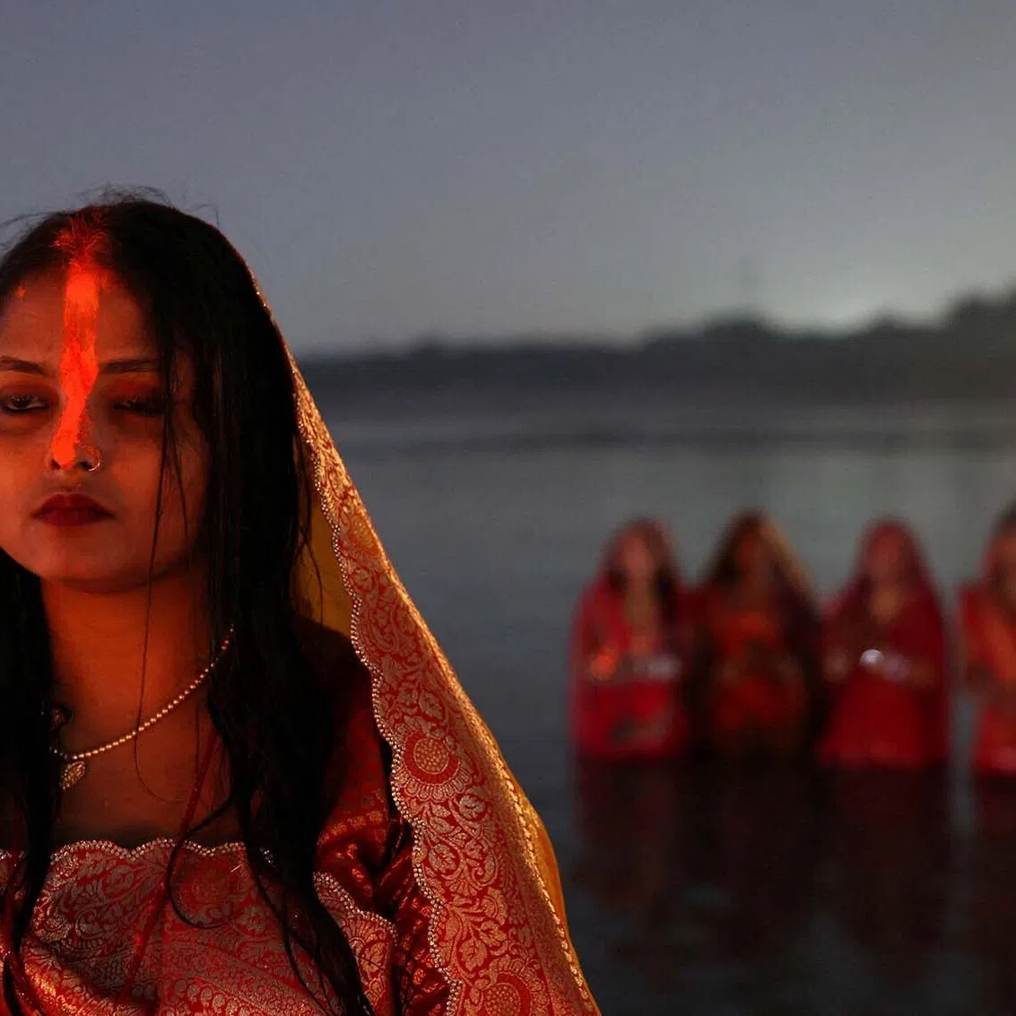 A Hindu woman with "sindhur", or vermilion powder, on her forehead stands in water as she worships the Sun god at the bank of the river Yamuna during the Hindu religious festival of Chhath Puja in Noida, India, October 28, 2025. REUTERS/Bhawika Chhabra TPX IMAGES OF THE DAY