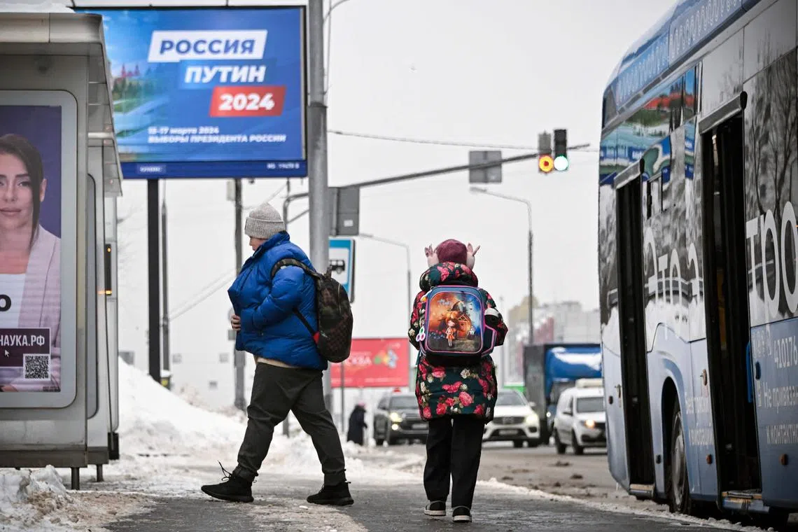 People walk past an election campaign billboard of Russian President Vladimir Putin in western Moscow.