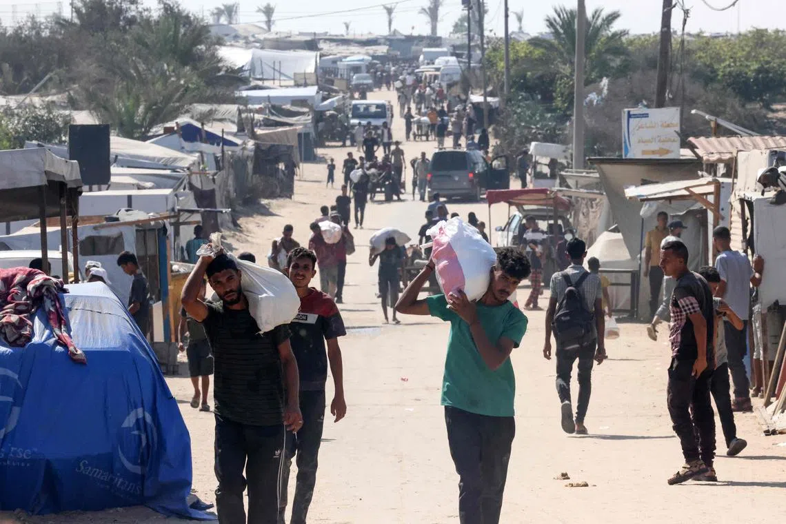 People carry food parcels in the al-Mawasi camp in Rafah in the southern Gaza Strip, that were picked up from the Rafah corridor on July 27, 2025. (Photo by AFP)