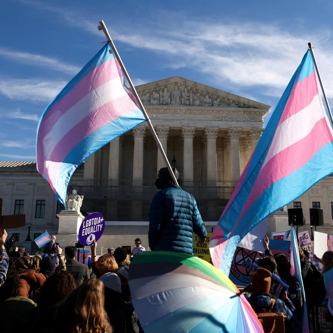 FILE PHOTO: Demonstrators carry a transgender flags outside the U.S. Supreme Court, on the day the justices heard oral arguments in two cases concerning efforts to enforce Republican-backed state laws banning transgender athletes from female sports teams at public schools, in Washington, D.C., U.S., January 13, 2026. REUTERS/Kevin Lamarque/File Photo