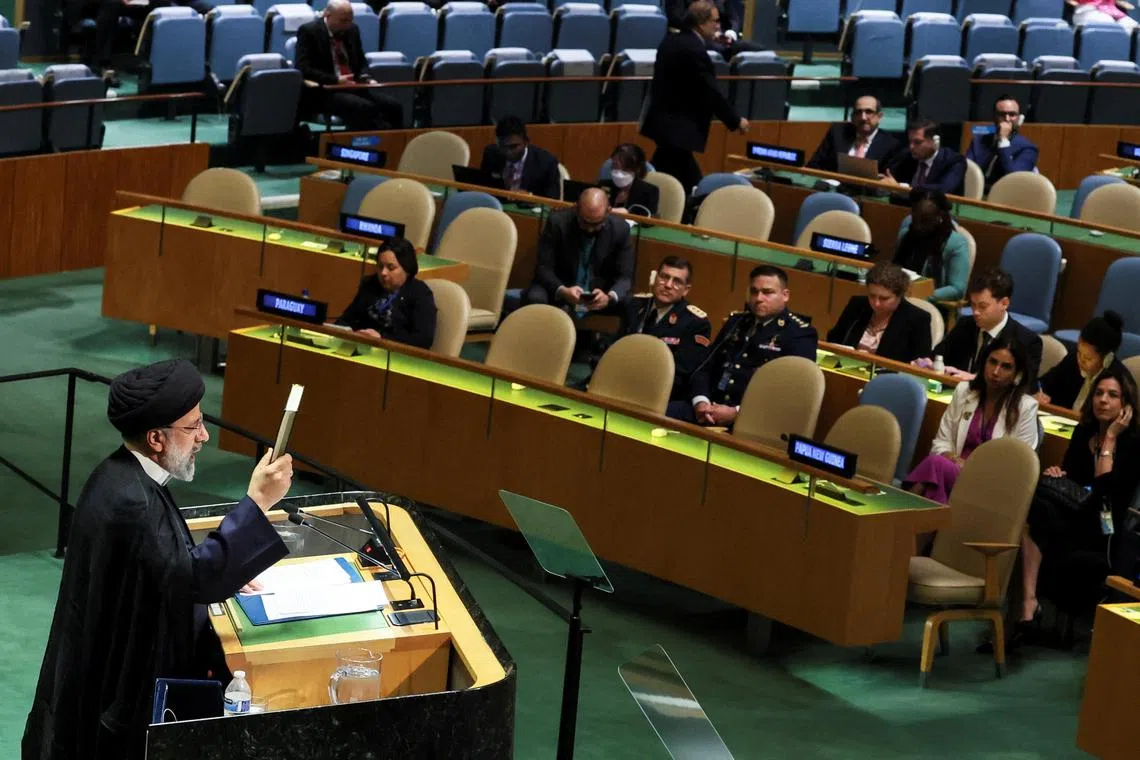 Iran's President Ebrahim Raisi holds up the Quran as he addresses the 78th Session of the UN General Assembly.