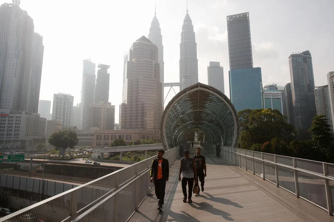 Men walk through as Kuala Lumpur City Center is shrouded by haze in Kuala Lumpur, Malaysia October 3, 2023. REUTERS/Hasnoor Hussain