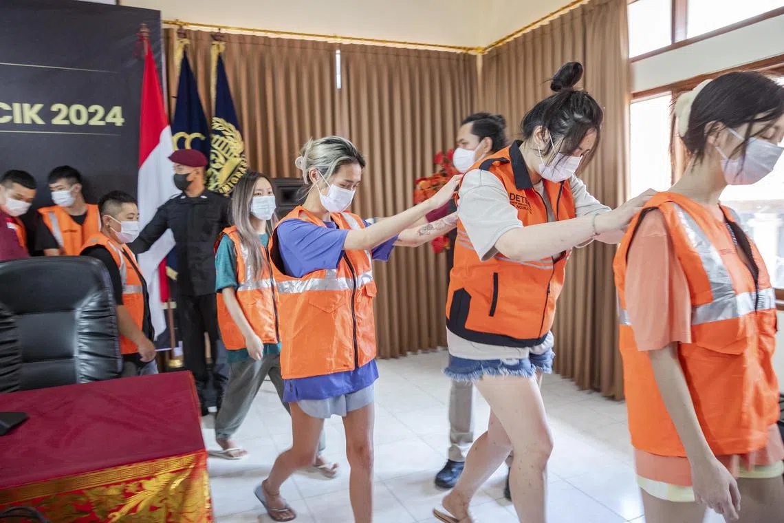 epa11442598 Indonesian authorities escort a group detained Taiwan nationals during a press conference at the Immigration Detention Center in Bali, Indonesia, 28 June 2024. A total of 103 Taiwanese nationals suspected of committing cybercrime were arrested by Indonesian immigration officers and police at a resort in Tabanan, Bali, on 26 June 2024.  EPA-EFE/MADE NAGI
