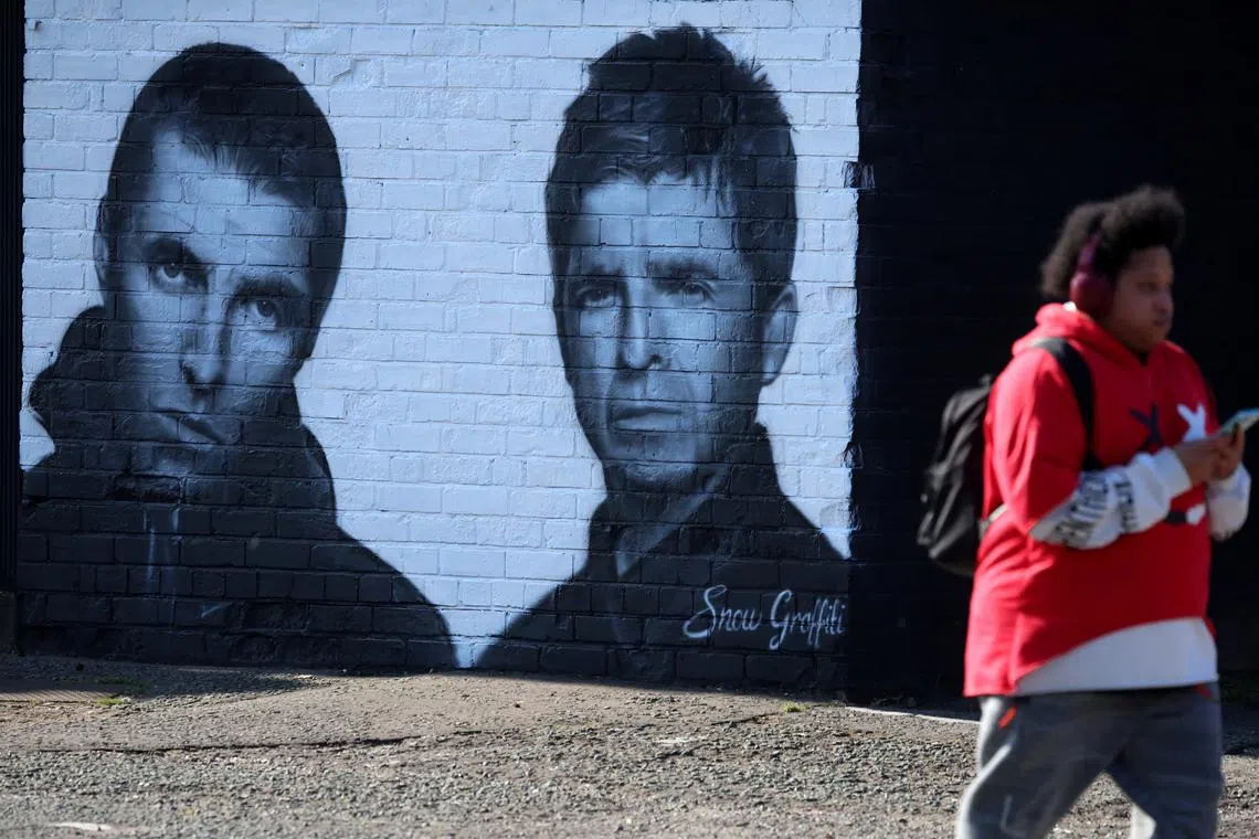 A man walks past a mural of Oasis band members Liam and Noel Gallagher by artist Snow Graffiti on the wall of the Coach and Horses pub in Whitefield, near Manchester, Britain, August 31, 2024. REUTERS/Phil Noble