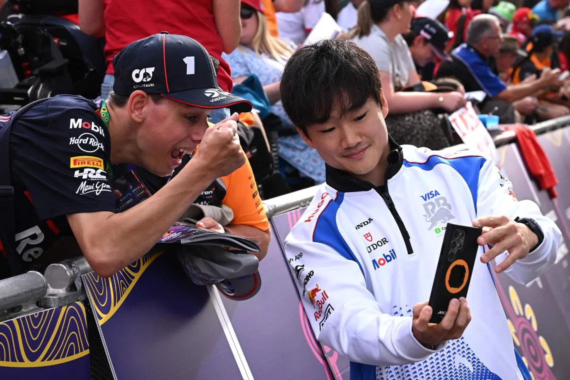 RB's Japanese driver Yuki Tsunoda (right) takes selfies with fans as he arrives at the Albert Park circuit in Melbourne on March 15.