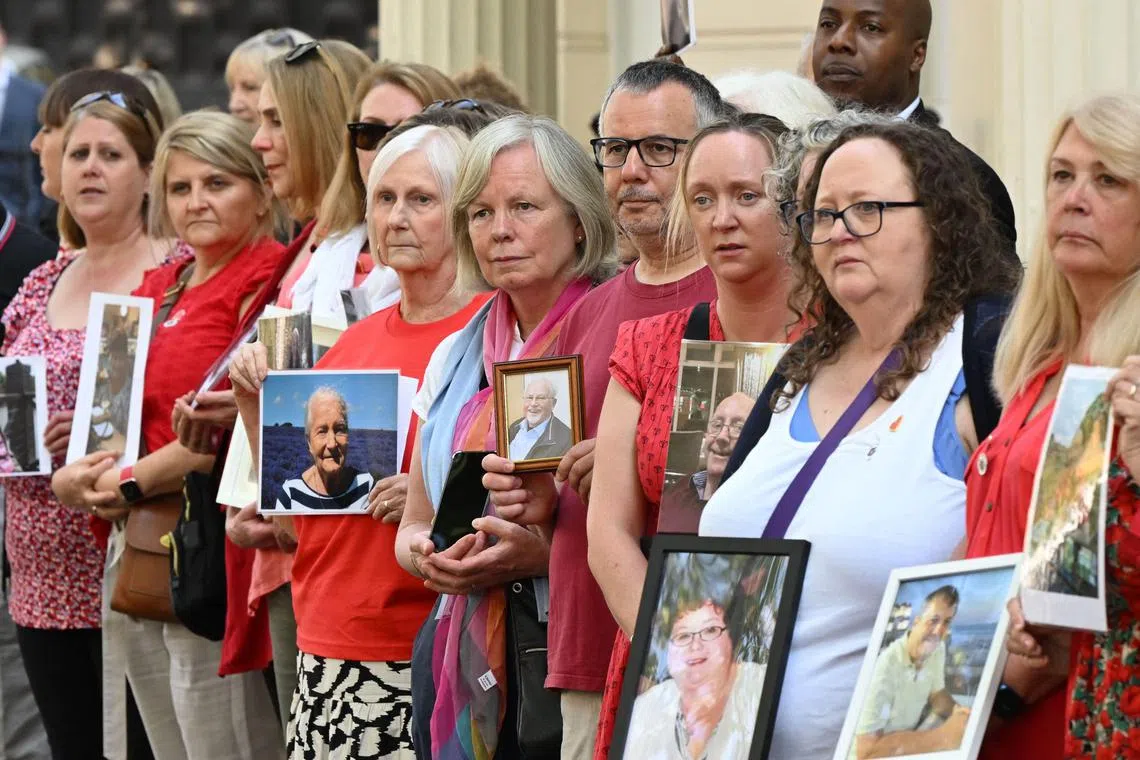 Members of the Covid-19 Bereaved Families for Justice hold photos of relatives who died during the pandemic in London on June 13.