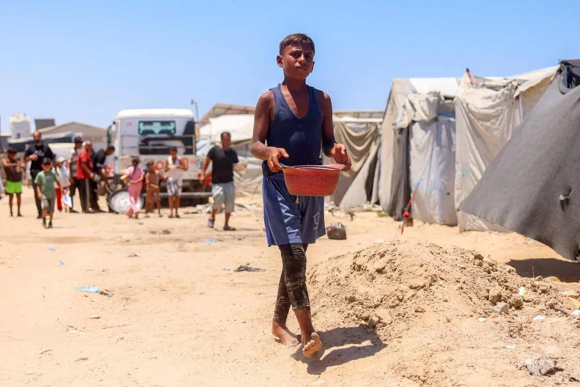 A boy walking with a pot in a camp for people displaced by war in Khan Younis in the southern Gaza Strip on July 11.