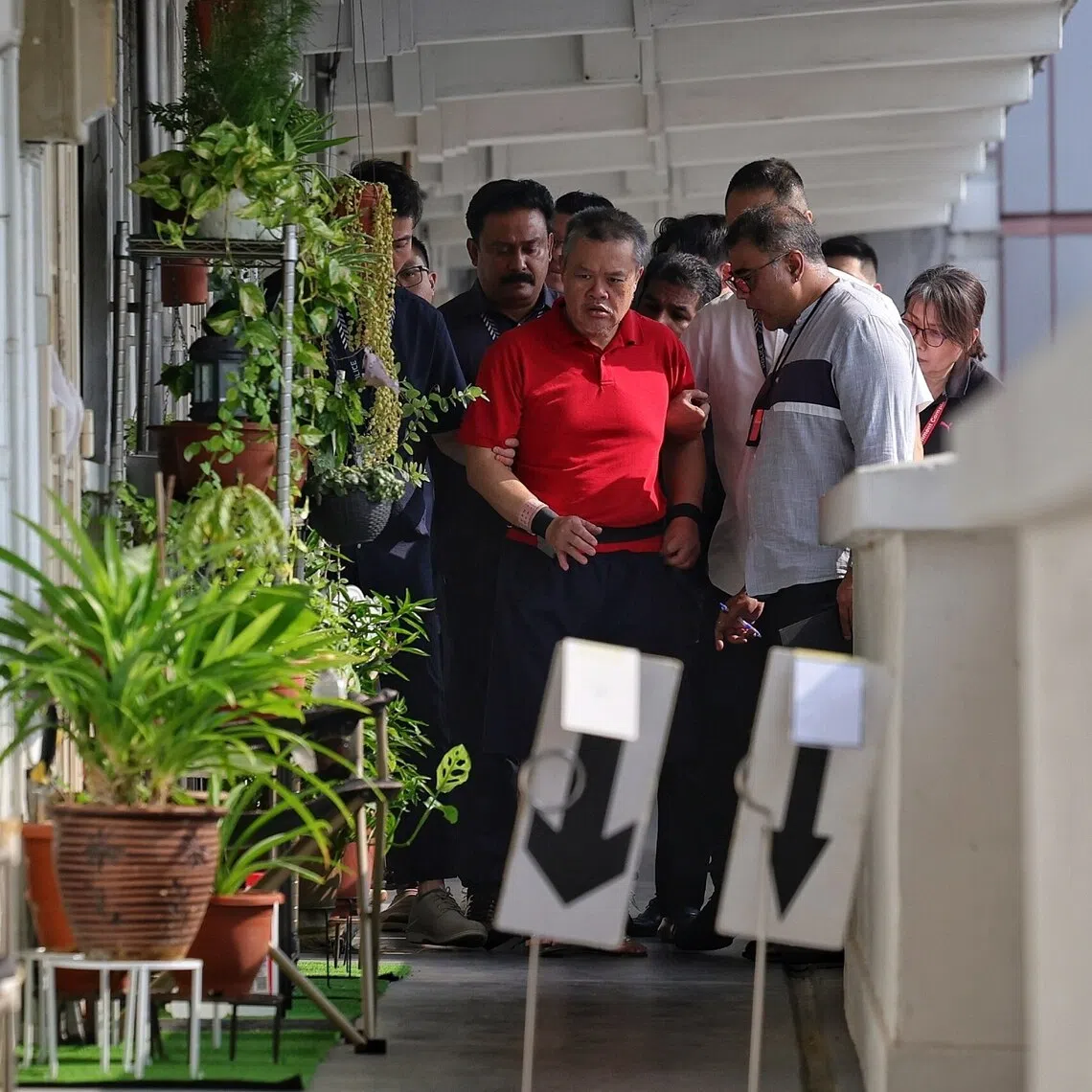 Police bringing Ng Swee Seng, who is accused of murdering his neighbour, Thiyagarajan Karunakaran, at Block 55 Lengkok Bahru, back to the scene on Aug 25.