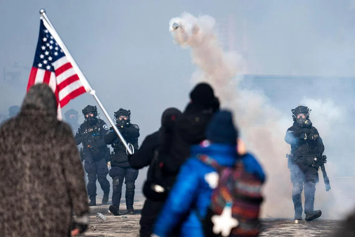 A Minneapolis police officer throwing a can of tear gas at people gathered on Nicollet Avenue following a fatal shooting by federal agents.