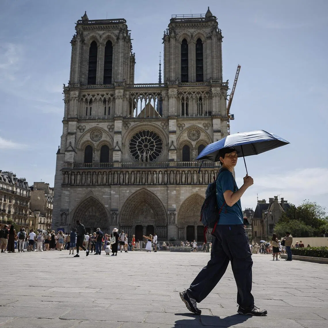 A tourist sheltering from the sun under an umbrella in front of Notre-Dame Cathedral in Paris on May 28.