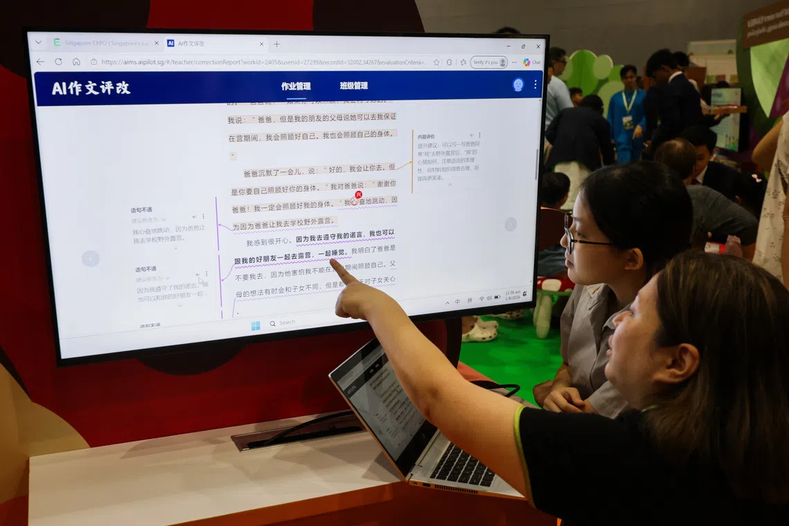 Goh Zi Qi Ieflt), 16, Jurong secondary school; and Oh Sze Wee, Chinese language subject head at Jurong Secondary School demonstrating the AI marking system (AIMS).