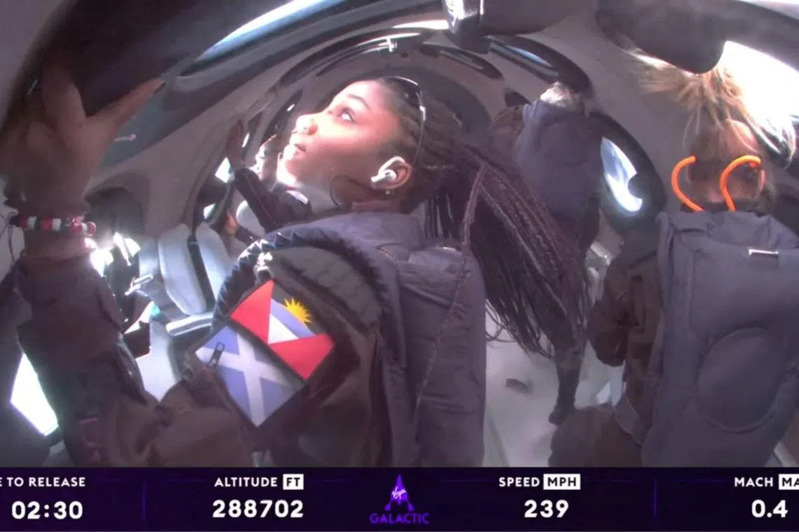 Anastatia Mayers (front left), 18, Jon Goodwin (back right), 80, and chief astronaut instructor Beth Moses (front right) view space from Virgin Galactic's VSS Unity.