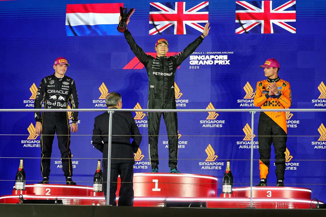 Race winner Mercedes' George Russell (centre), second-placed Red Bull's Max Verstappen (left), and McLaren's Lando Norris (right) on the podium after the 2025 Formula One Singapore Airlines Singapore Grand Prix at the Marina Bay Street Circuit on Oct 5, 2025. 