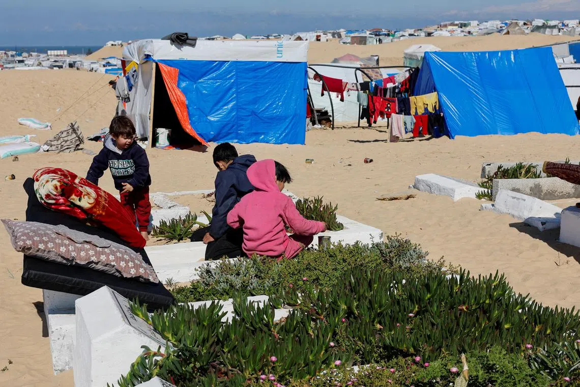 Displaced Palestinian children, who fled their houses due to Israeli strikes, play in a cemetery where they shelter, in Rafah, southern Gaza Strip, on Feb 5.