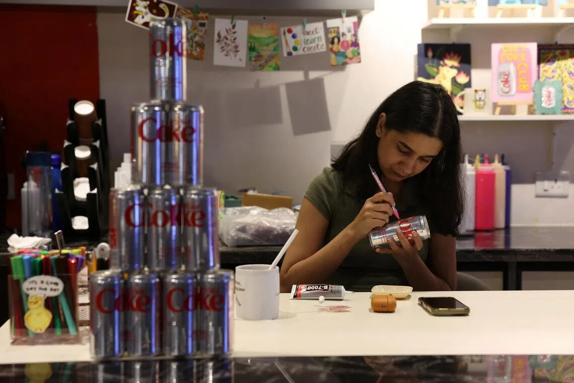 A woman using rhinestones to decorate a diet coke can for an upcoming Diet Coke party in New Delhi on May 5. 