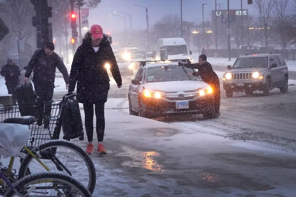 Pedestrians navigate a snow-covered sidewalk as temperatures hang in the single-digits on Dec 22, 2022 in Chicago, Illinois.