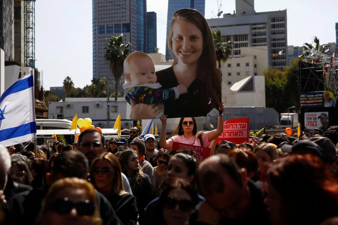 A woman holds a cut-out picture of hostages Shiri Bibas, 32, with Kfir Bibas, 9 months old, who were kidnapped from their home in Kibbutz Nir Oz during the deadly October 7, 2023 attack by Hamas and then killed in Gaza, on the day of their funeral procession, at a public square dedicated to hostages in Tel Aviv, Israel February 26, 2025.  REUTERS/Shir Torem