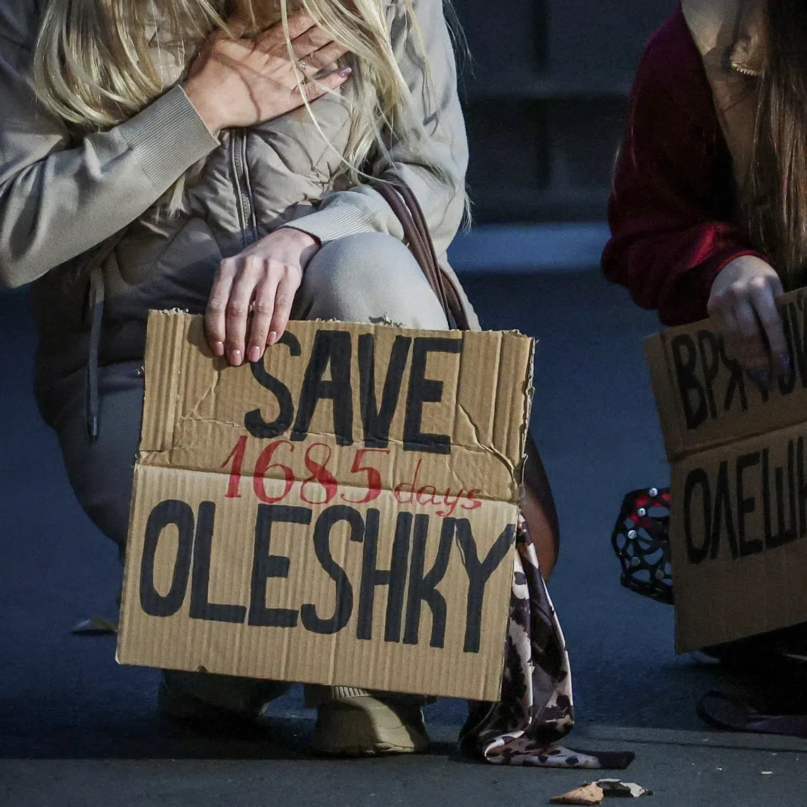 A dog looks on while women hold posters in Kyiv as they participate in a rally demanding the establishment of a humanitarian corridor to evacuate Ukrainian civilians from the town of Oleshky in Kherson region, Ukraine, on Oct 6.