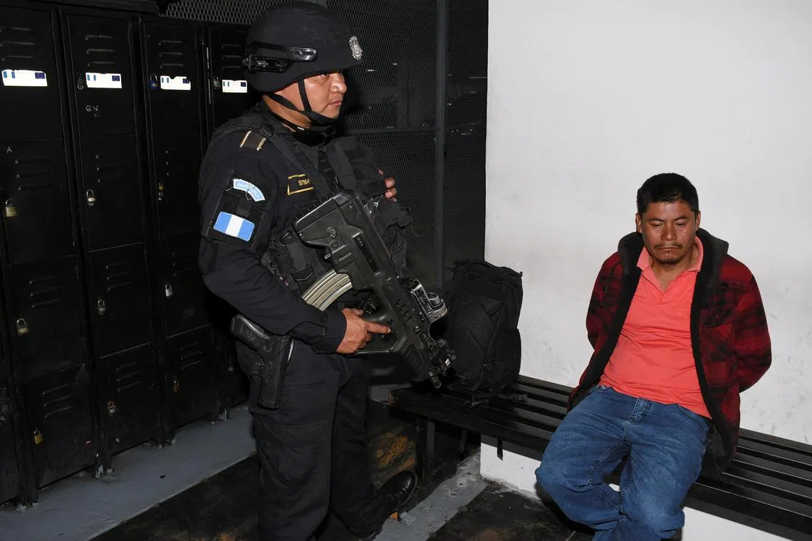 FILE PHOTO: A police officer stands next to Rigoberto Ramon Miranda Orozco, suspected on smuggling charges over the deaths of 53 migrants on a sweltering truck in Texas in 2022, at a court in Guatemala City, Guatemala, August 21, 2024. REUTERS/Stringer/File photo
