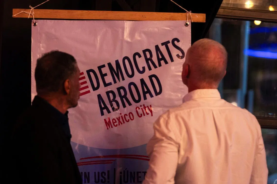 FILE PHOTO: People observe the sign of the Democrats Abroad organization during the first debate between U.S. President Joe Biden and former President Donald Trump, at the Pinche Gringo BBQ restaurant, in Mexico City, Mexico June 27, 2024. REUTERS/Quetzalli Nicte-Ha/File Photo