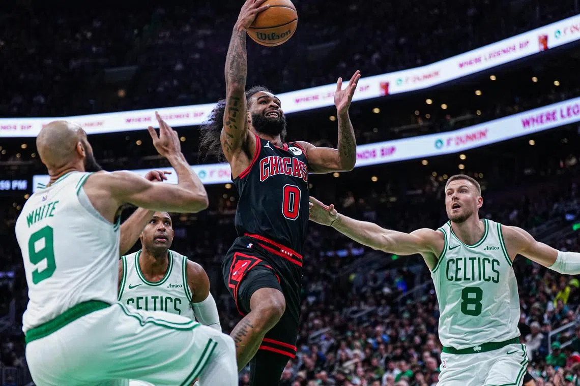 Chicago Bulls guard Coby White drives to the basket against Boston Celtics guard Derrick White and centre Kristaps Porzingis in the second half at TD Garden.