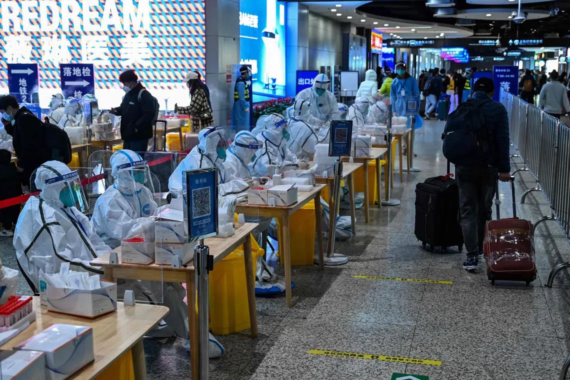 TOPSHOT - Health workers wait to test passengers for the Covid-19 coronavirus after their arrival at Hongqiao railway station in Shanghai, on December 6, 2022. (Photo by HECTOR RETAMAL / AFP)