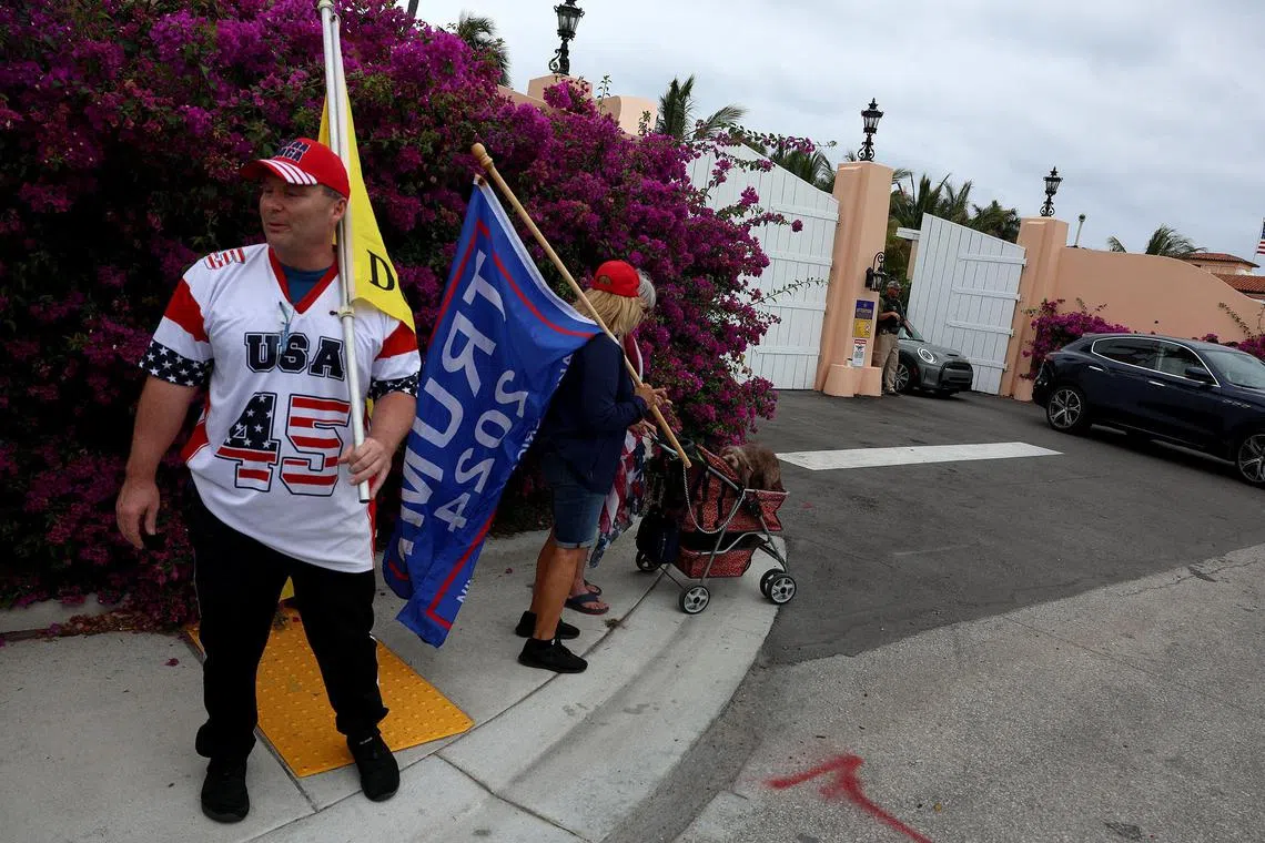 PALM BEACH, FLORIDA - MARCH 19: Supporters of former President Donald Trump gather near an entrance to his Mar-a-Lago home on March 19, 2023 in Palm Beach, Florida. Trump said on a social media post that he expects to be arrested in connection with an investigation into a hush-money scheme involving adult film actress Stormy Daniels and called on his supporters to protest any such move. However, it is unclear if he will be arrested or not.   Joe Raedle/Getty Images/AFP (Photo by JOE RAEDLE / GETTY IMAGES NORTH AMERICA / Getty Images via AFP)