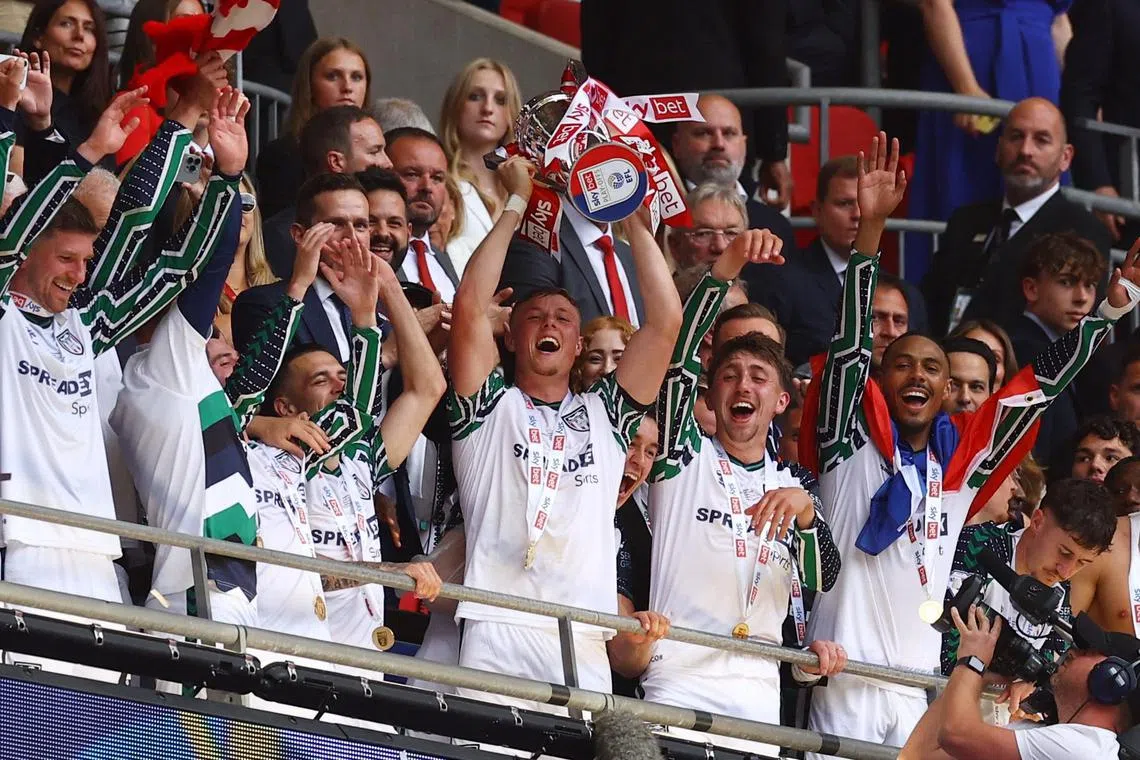 Sunderland's Daniel Ballard lifts the Championship trophy as he celebrates with teammates.