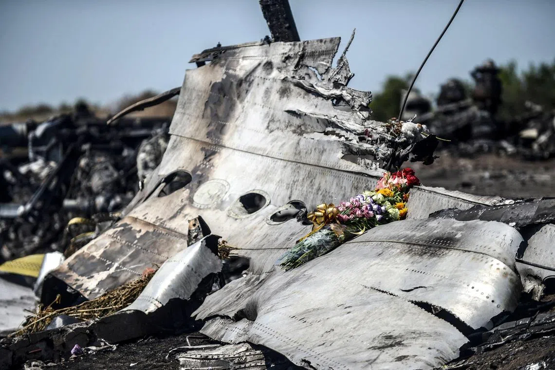 (FILES) This photograph shows flowers, left by parents of an Australian victim of the crash on a piece of the Malaysia Airlines flight MH17, near the village of Hrabove (Grabove), in the Donetsk region on July 26, 2014. The families of the victims of the downing of flight MH17 in war-torn eastern Ukraine are this week commemorating ten years since the tragedy, with dwindling hopes of seeing those responsible behind bars. (Photo by Bulent KILIC / AFP)