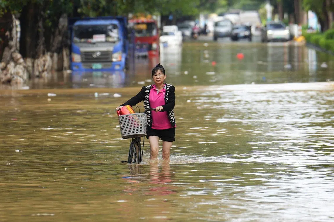 A woman walks her bicycle through a street flooded by heavy rains from Typhoon Sanba in Maoming, in China’s southern Guangdong province on October 21, 2023. The 2023 United Nations Climate Change Conference COP28 will be held from November 30 to December 12, 2023, in Dubai. (Photo by AFP)
