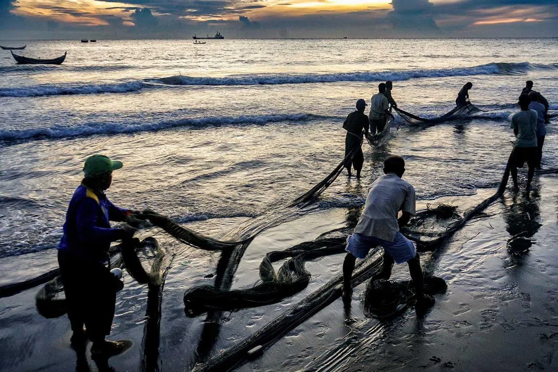 Fishermen pull a net at sunrise on the coast of Hagu Village in Lhokseumawe, Indonesia, June 7.