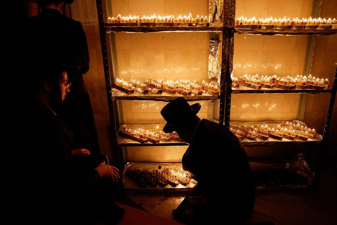 Members of the Erlau Jewish Hasidic dynasty lighting 138 Hanukkiyot, candlesticks with nine branches that are lit to mark the Jewish holiday of Hanukkah, for people who are believed to be held hostage by Palestinian Islamist group Hamas in the Gaza Strip, at a Jewish seminary in Jerusalem, Dec 13, 2023.