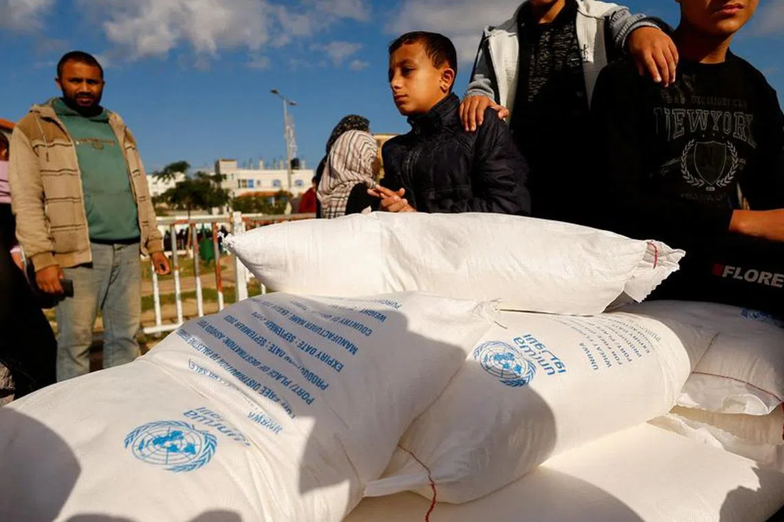 FILE PHOTO: Palestinians receive flour bags distributed by UNRWA in Rafah, in the southern Gaza Strip November 21, 2023. REUTERS/Ibraheem Abu Mustafa/File Photo